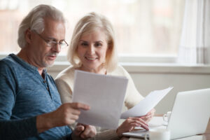 Older age couple looking at documents with open laptop