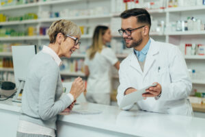 Male pharmacist explaining prescription to woman at counter.